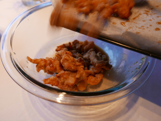 Dropping the crisp chicken from the pan to the bowl